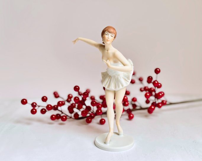 Porzellanballerina vor Arrangement aus roten Beeren.